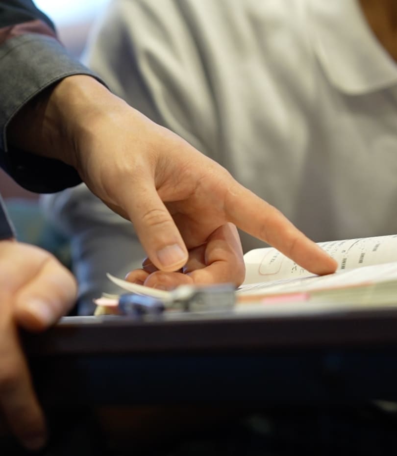 写真：講師が生徒の教科書を指で指し示して教える様子